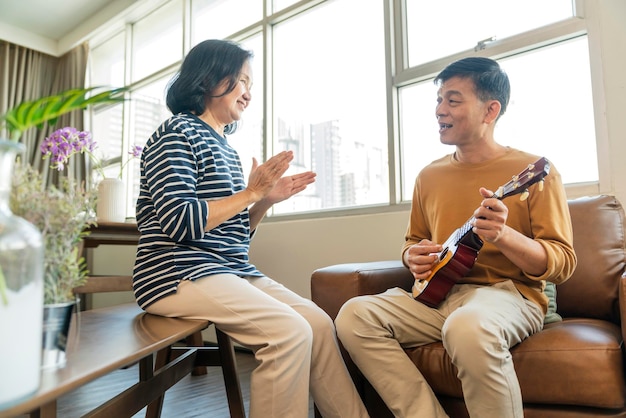 Sweet Asian senior Couple sing play acoustic ukulele instrument Happy Smiling Elderly grandparent having fun and enjoying their Retirement life Lifestyle Party happy lifestyle