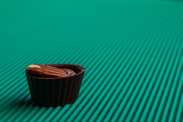 Sweet assorted chocolate candy on green wavy surface. Delicious unhealthy food concept.