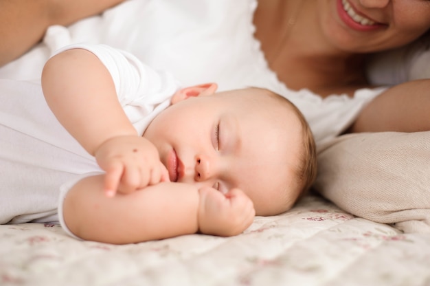 Sweet baby boy sleeping in bed with his mother.