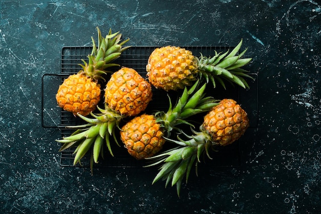 Sweet baby pineapple on a black stone background Tropical fruits Top view Free space for text