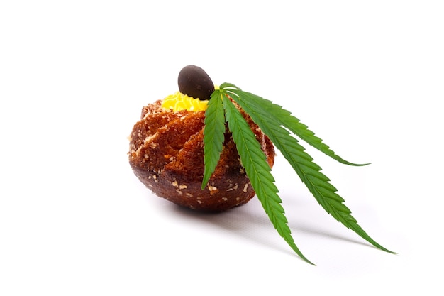 Sweet baked goods with cannabis oil. cupcake with a leaf of marijuana close-up isolated on white background.