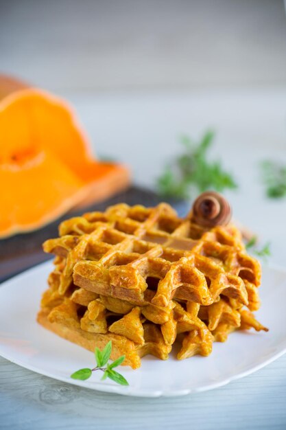 sweet baked pumpkin waffles with honey in a plate on a wooden table