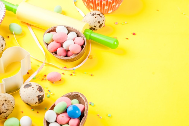 Sweet baking concept for Easter, cooking  with baking - with a rolling pin, whisk for whipping, cookie cutters, quail eggs, sugar sprinkling. Bright yellow  , top view  copyspace