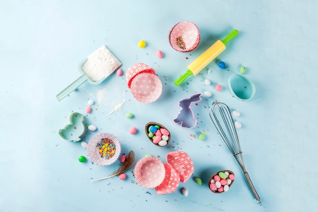 Sweet baking  for Easter,  cooking  with baking  with a rolling pin, whisk for whipping, cookie cutters, sugar sprinkling, flour. Light blue background, top view 