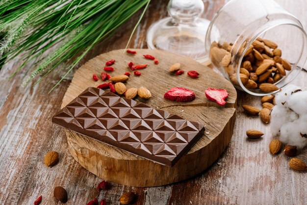 Сладкая плитка шоколада с фруктами и орехами на деревянном фоне