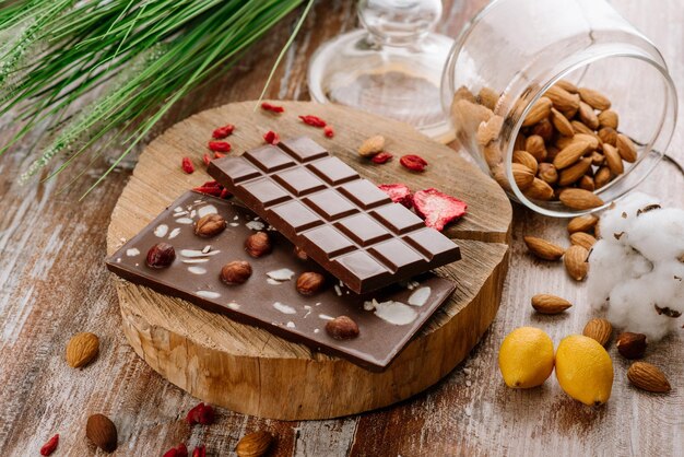 Sweet bar of chocolate with fruits and nuts on the wooden background