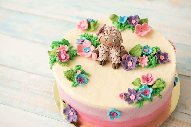 Sweet birthday cake decorated with flowers and sugar sheep