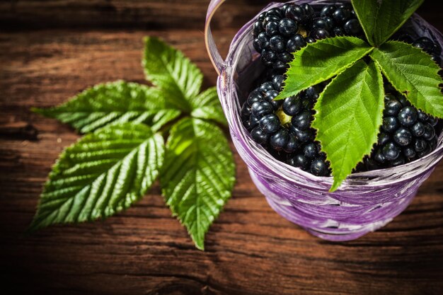 Sweet blackberries in basket leaf on vintage wooden board