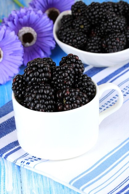 Sweet blackberries in cup on table closeup