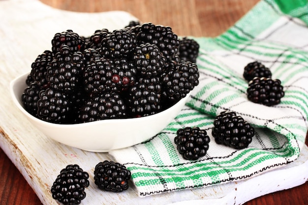 Sweet blackberry in bowl on wooden table