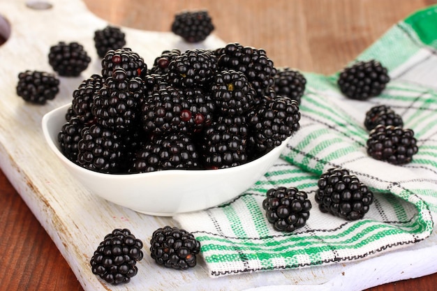 Sweet blackberry in bowl on wooden table