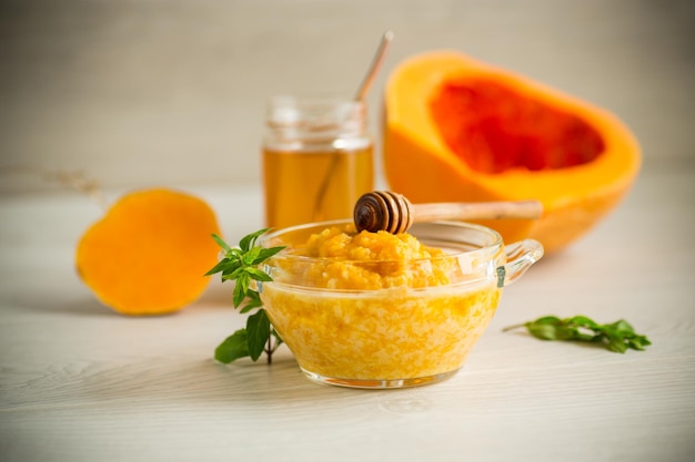 Sweet boiled pumpkin porridge in a bowl with honey on a light wooden table