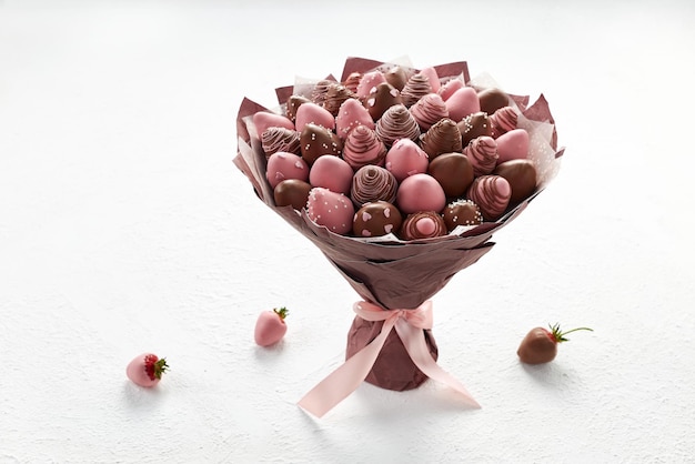 写真 白い背景の上の茶色とピンクのチョコレートで覆われたイチゴの甘い花束