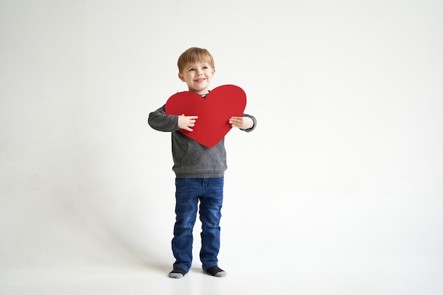 Sweet boy holding red paper heart on white background valentines day or kids healthcare medical concept