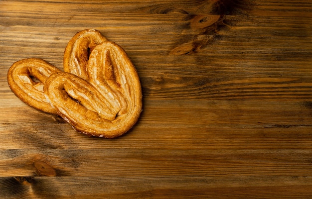 Pasticceria palmiers intrecciata dolce, cuore di palma o orecchio di elefante su sfondo scrivania tavolo in legno. pasta sfoglia francese o pate feuilletee vista dall'alto con spazio copia