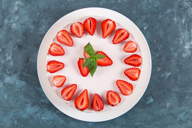 Sweet breakfast delicious cheesecake with fresh strawberries and mint homemade recipe without baking on a dark blue stone table Copy space