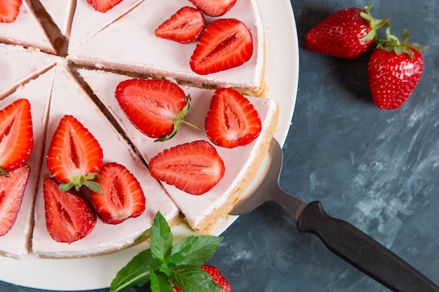 Sweet breakfast delicious cheesecake with fresh strawberries and mint homemade recipe without baking on a dark blue stone table Copy space