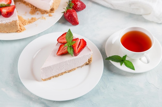 Sweet breakfast tea and delicious cheesecake with fresh strawberries and mint homemade recipe without baking on a blue stone table Copy space