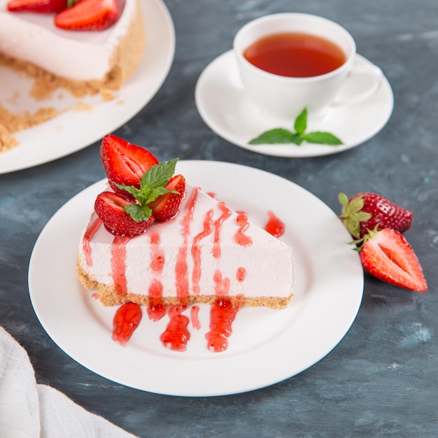 Photo sweet breakfast tea and delicious cheesecake with fresh strawberries and mint homemade recipe without baking on dark blue stone table copy space