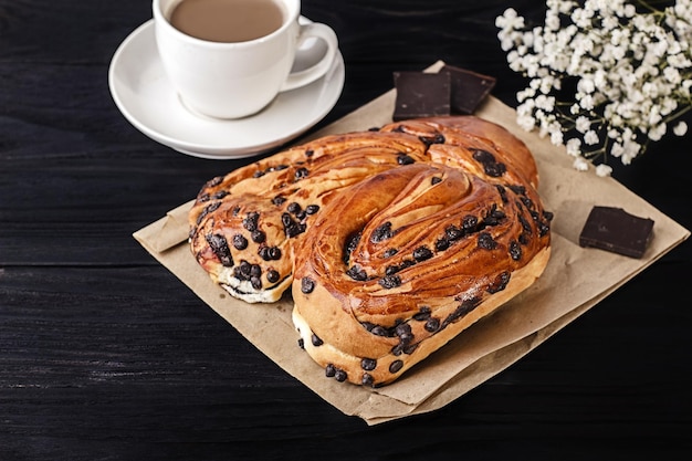 Sweet bun with chocolate pieces on a dark background