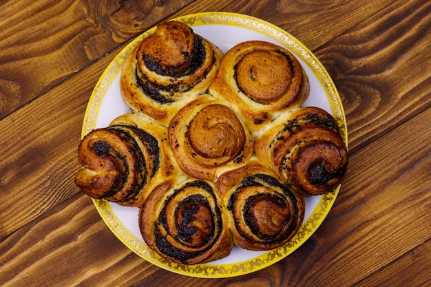 Sweet bun with poppy seeds on wooden table Top view