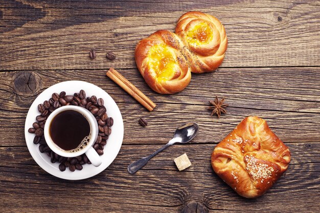 Sweet buns and coffee cup on old wooden table