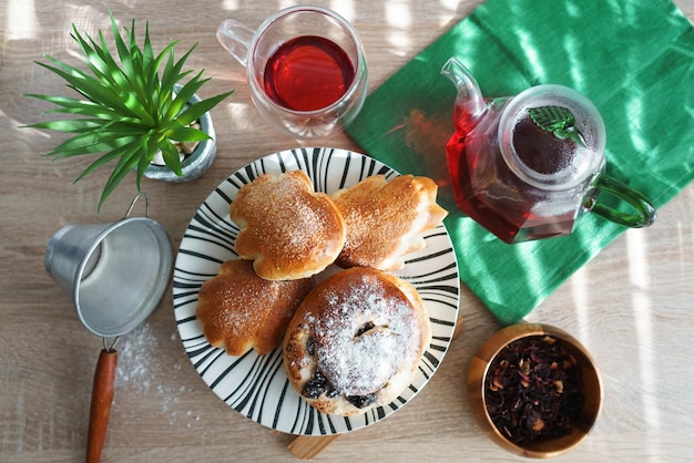 Sweet buns on a plate and hibiscus tea on a wooden table with natural light