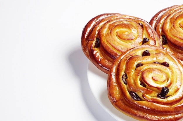 Sweet buns with raisins on white background