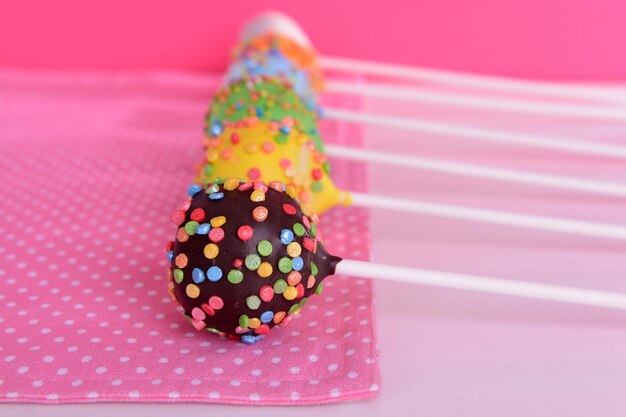 Sweet cake pops on table on pink background