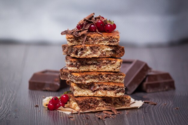 Sweet cake with cocoa powder and berries on dark wooden background