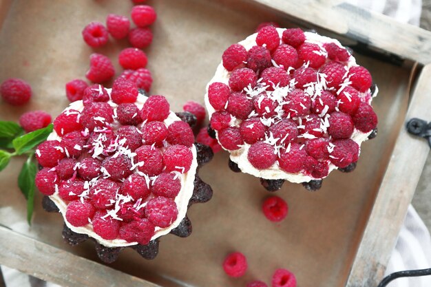 Sweet cakes with raspberries on wooden table background