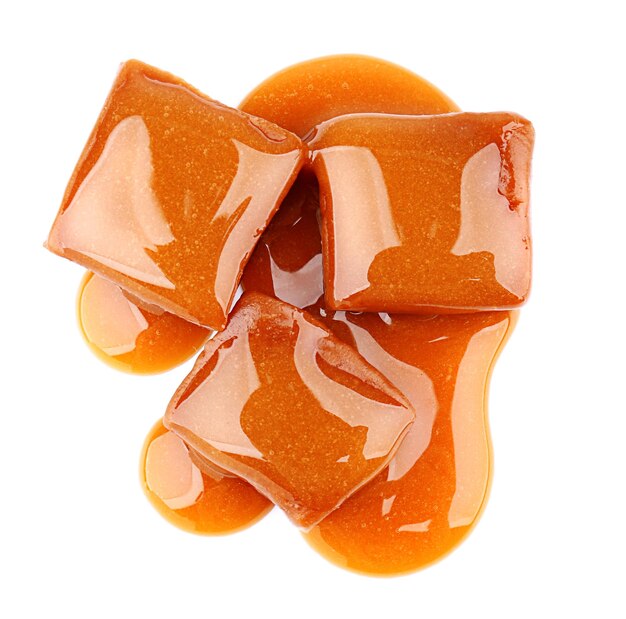 Sweet candies with caramel topping on white background