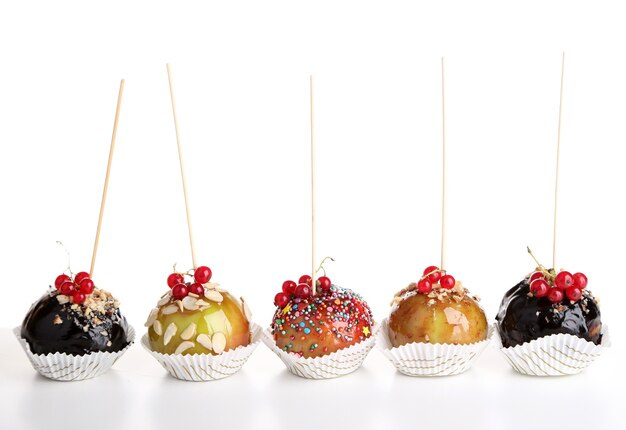 Sweet caramel apples on sticks with berries, on wooden table