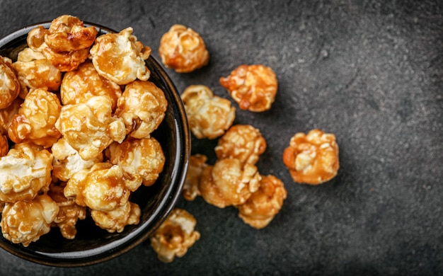 Sweet caramel popcorn in small black plate on dark