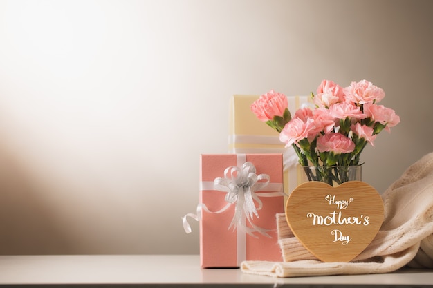 Photo sweet carnation flowers and gift on table