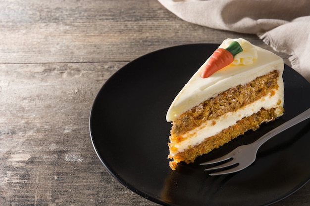 Sweet carrot cake slice on a plate on wooden table