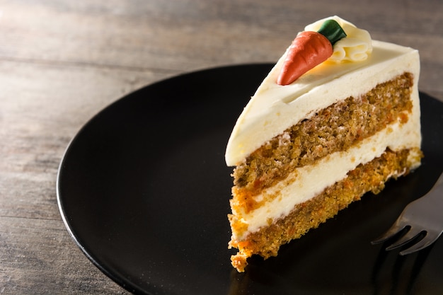 Sweet carrot cake slice on a plate on wooden table