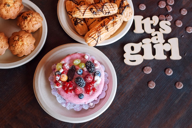 Sweet cheese cake with fresh berries and yoghurt cream and wooden sign Its A Girl. Baby shower party sweets.