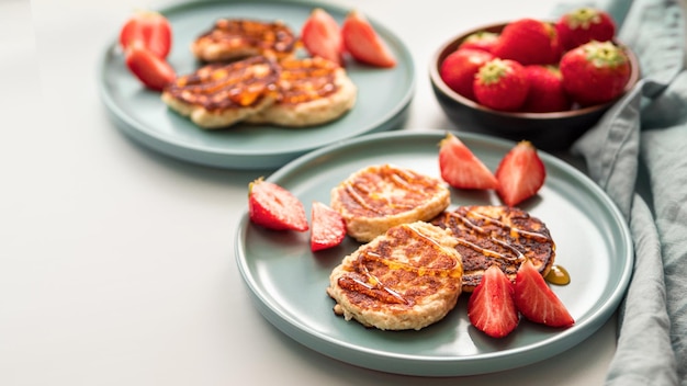 Sweet cheese pancakes on plate served strawberries Cottage cheese pancakes syrniki ricotta fritters curd fritters Copy space for text or design