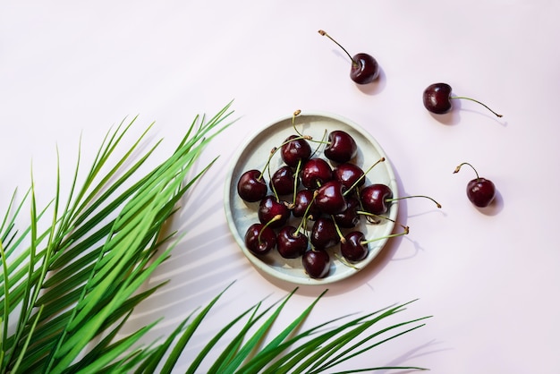 Sweet cherry berries in a plate with palm branches