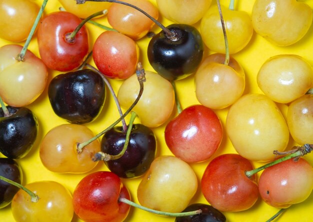 Sweet cherry with a stem on a yellow background bright table berries on the table