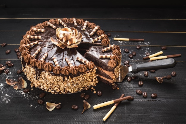黒い木製の背景においしいクリームと甘いチョコレートケーキ