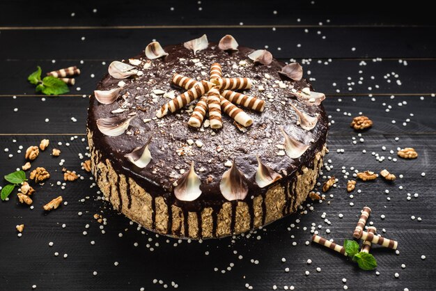 Sweet chocolate cake with tasty cream on the black wooden background