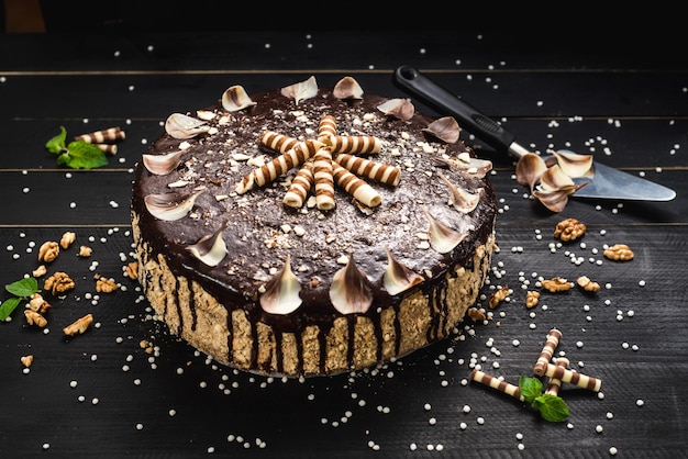 Sweet chocolate cake with tasty cream on the black wooden background