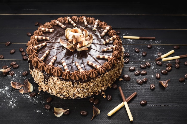 Sweet chocolate cake with tasty cream on the black wooden background