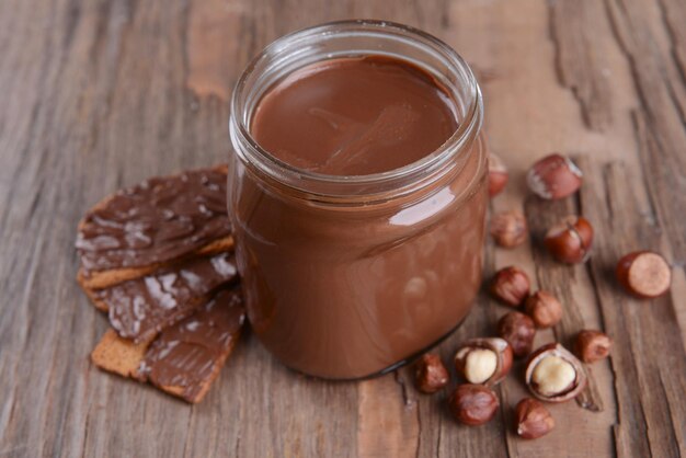 Sweet chocolate cream in jar on table closeup