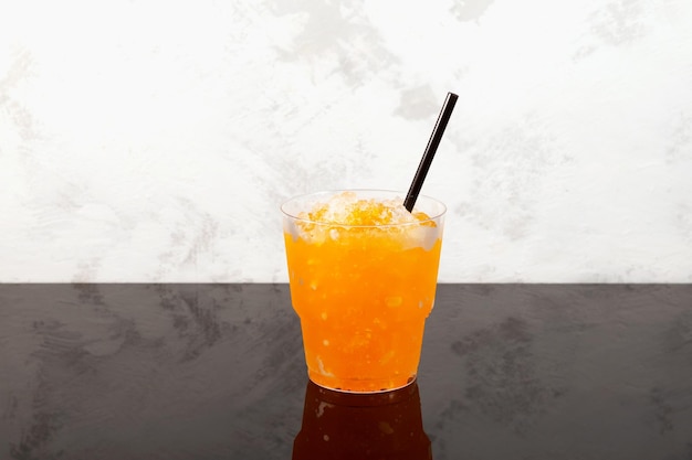 Sweet citrus Shaved ice Orange Granizado in plastic take away cup Refreshing Slushie drink