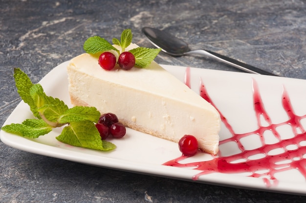 Dolce cheesecake classico decorato con menta ai frutti di bosco e salsa ai frutti di bosco