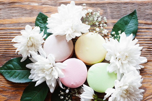 Sweet closeup photo of french traditional cookies. Lovely macaroon with flowers on the wooden table.