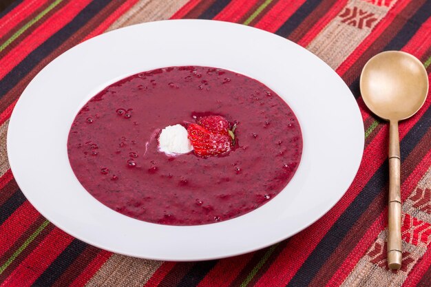 Sweet cold strawberry blueberry soup with fruit and ice cream close up